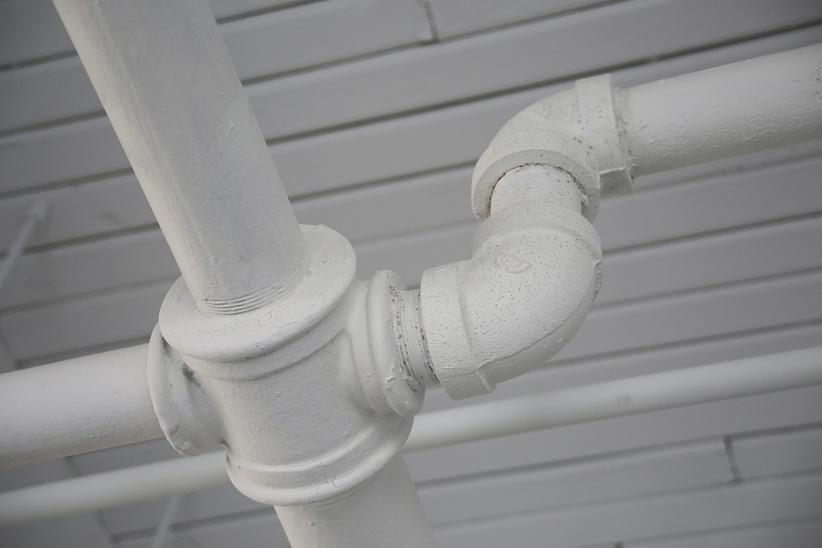 close up of white pipes in front of a white wall.