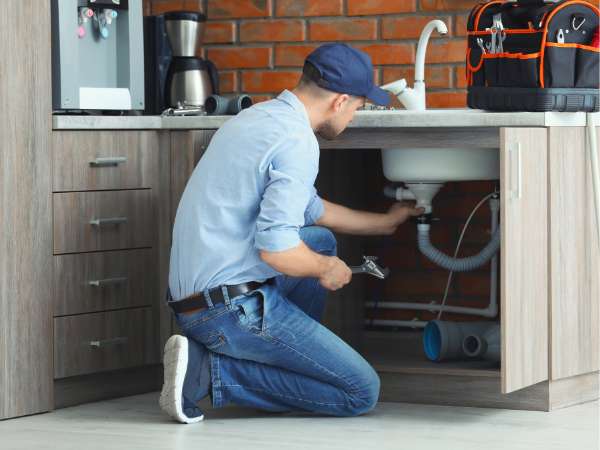 Professionally dressed plumber working under a sink